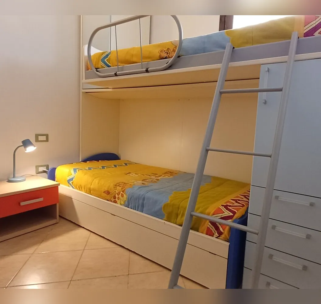 La seconda camera con il letto a castello, il letto singolo con lenzuola gialle e la scaletta